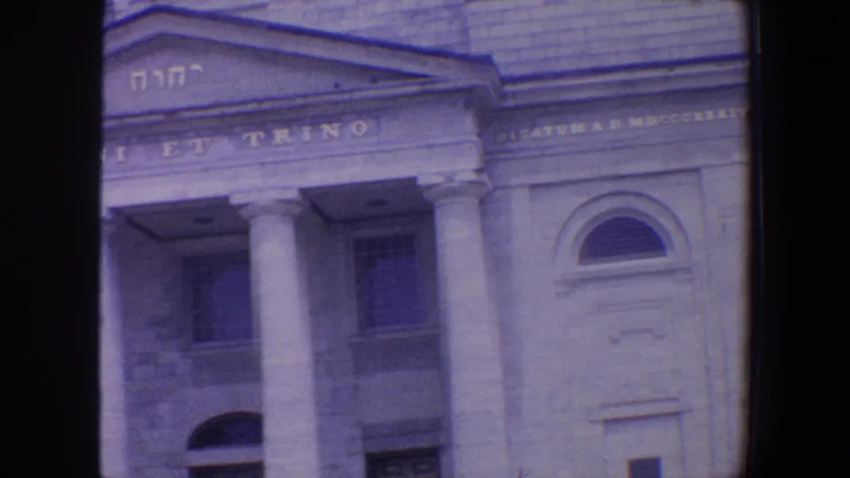1964 St. Louis home-movie view of the public hall entrance area with columns, arched doorway, stonework, and pediment text.