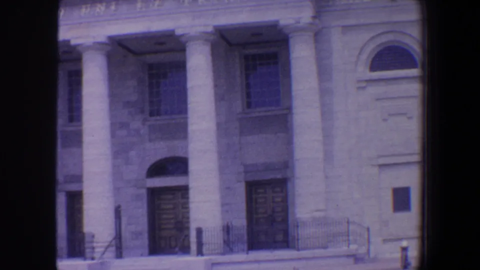 1964 St. Louis frame showing the public hall entrance with tall columns, double doors, arched windows, railings, and stone facade.