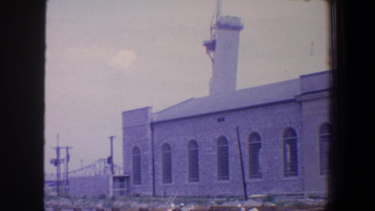 Similar view of the towered building with arched windows and roadside poles.