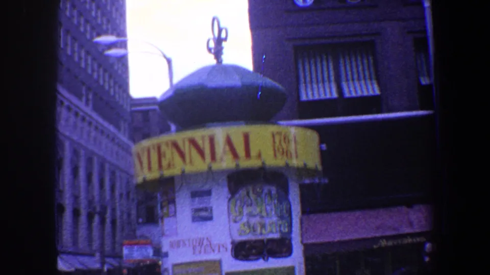 Close street-level view of the Centennial booth top, with 1764-1964 signage, building facades, awnings, and streetlights.