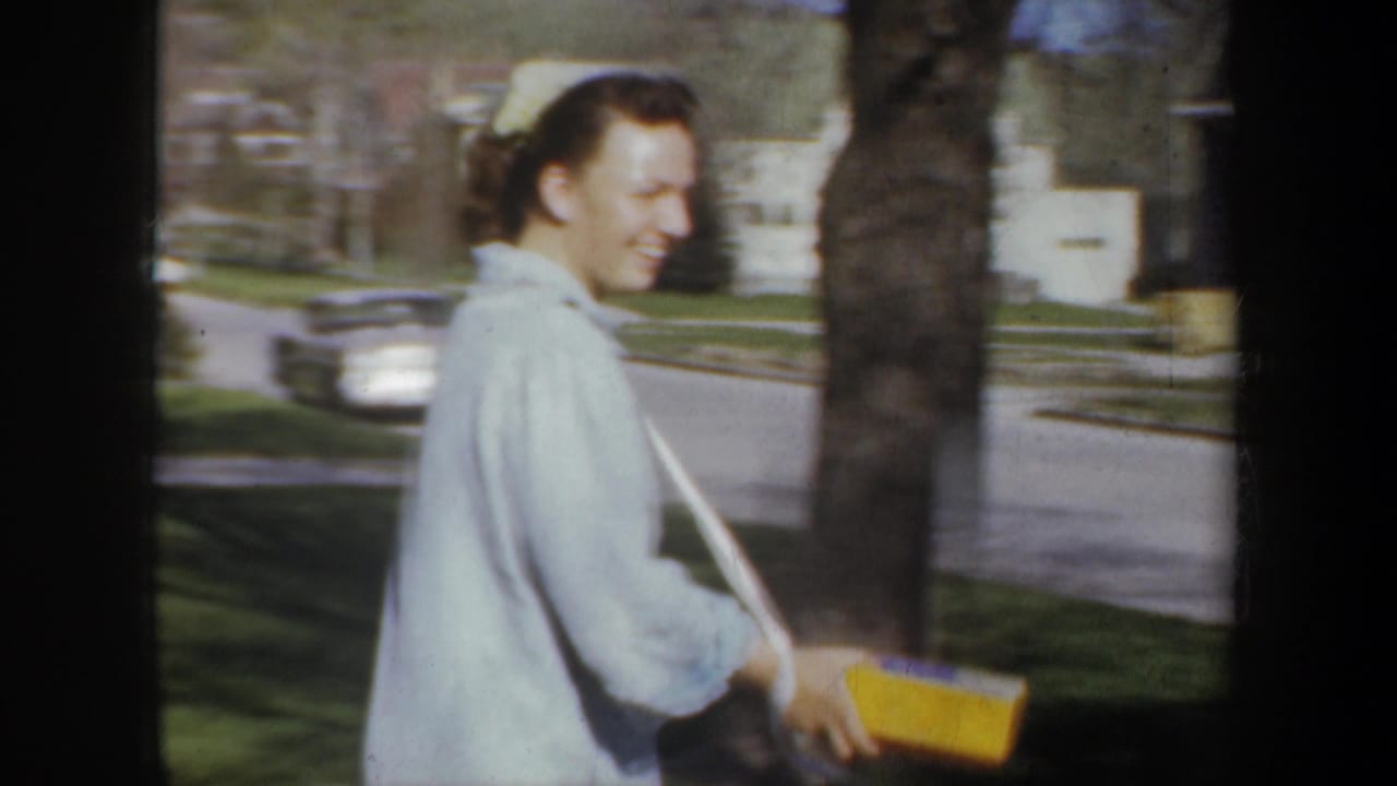 Young woman smiling while walking along a residential street with a yellow box.
