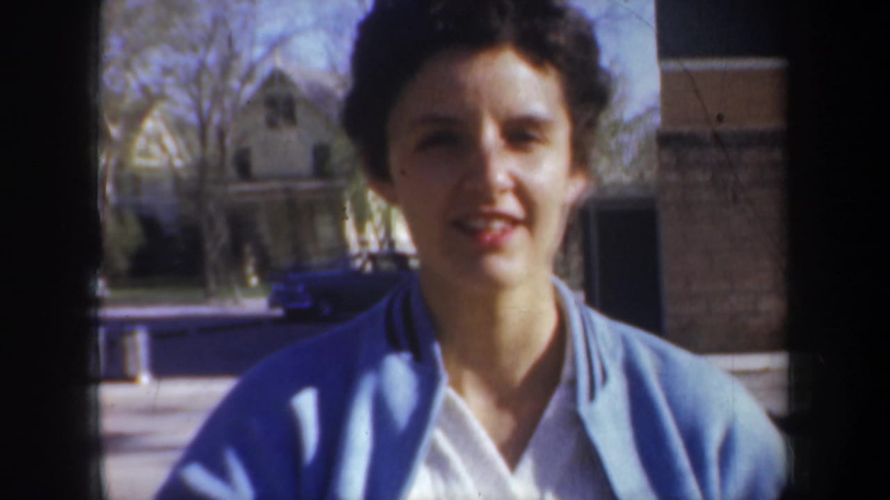 Close view of a woman in a blue jacket facing the camera outdoors.