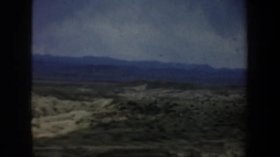 Wyoming scrubland and distant mountains appear through the moving car view in this 1957 8mm frame.