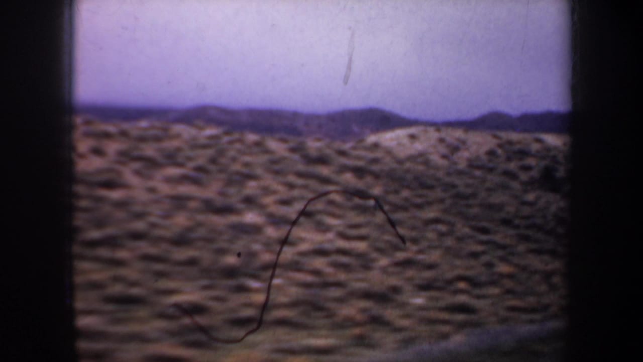 Wyoming countryside view from the 1957 8mm clip, showing scrub-covered hills and distant mountain ridges.