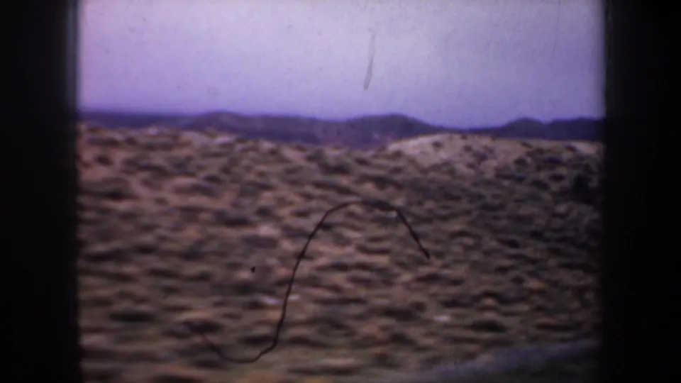 Wyoming countryside view from the 1957 8mm clip, showing scrub-covered hills and distant mountain ridges.