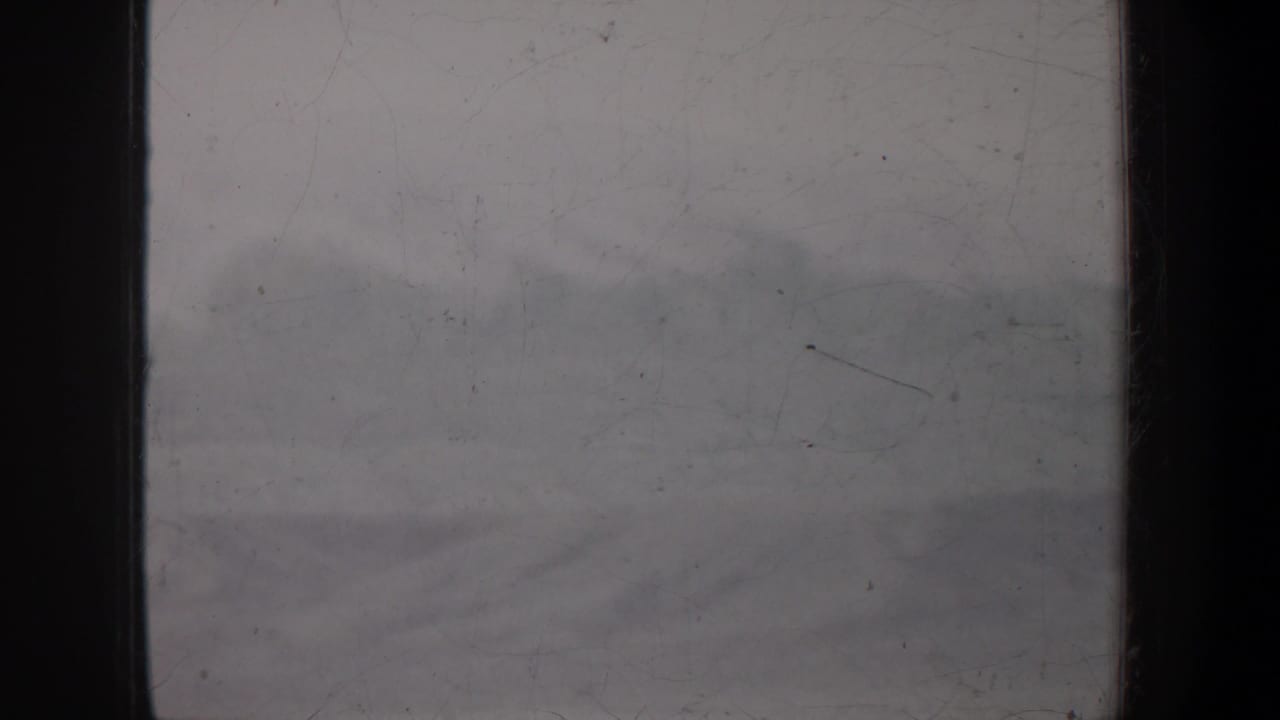 Low clouds over distant hills with muted sky and visible film wear.