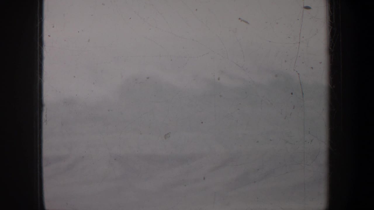 Soft cloud layer and faint hills seen through scratched 8mm film.