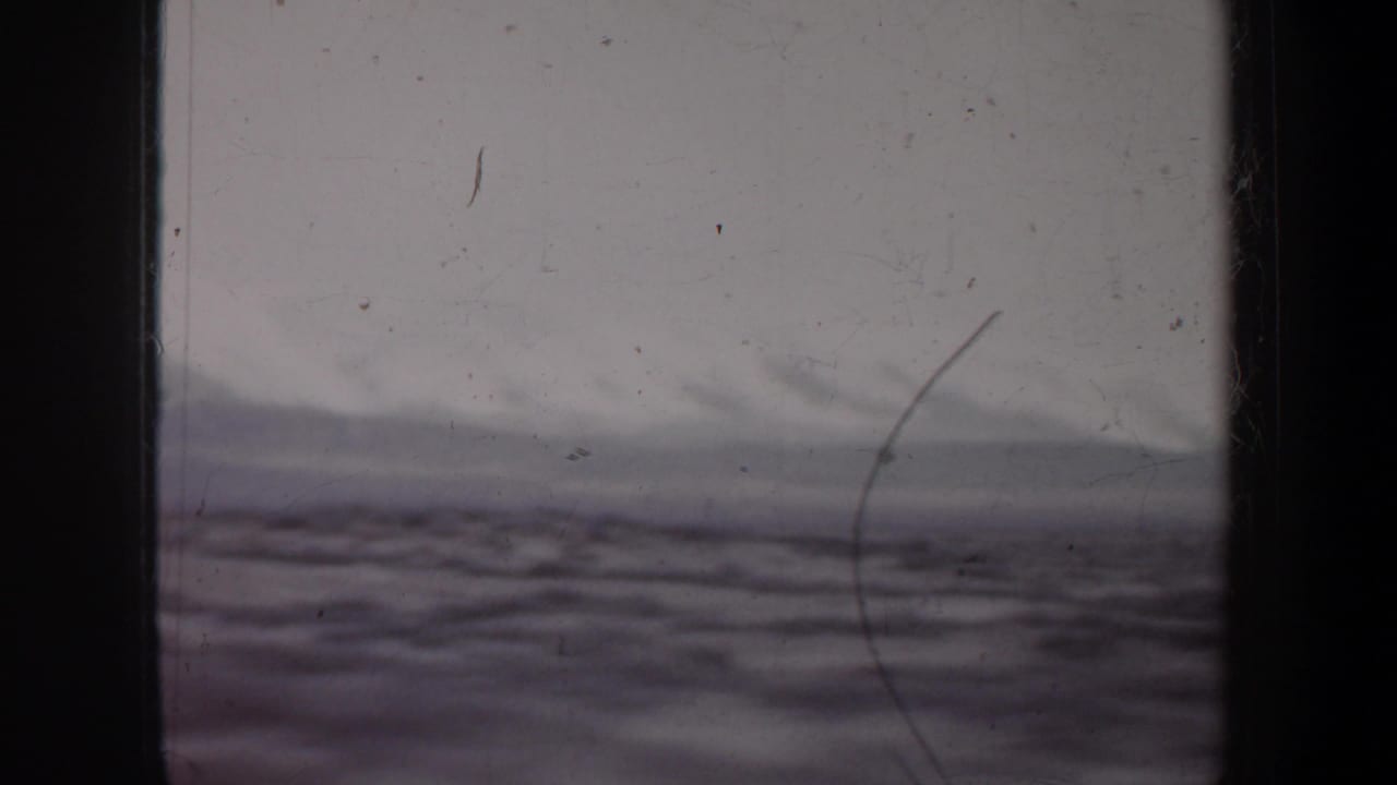 Cloudy horizon and rolling terrain seen through dark vertical frame edges.