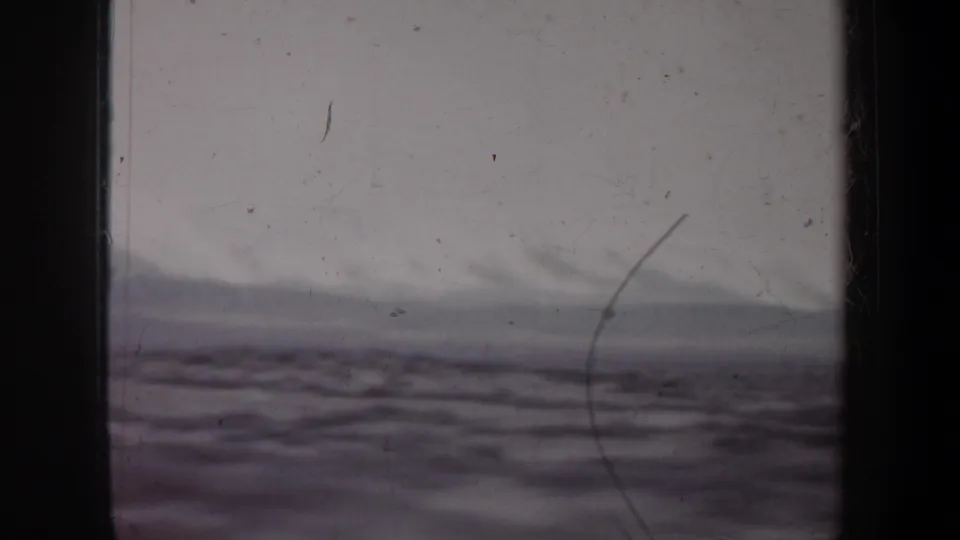 1957 Wyoming travel view showing distant cloudy hills and open terrain through a weathered 8mm frame.