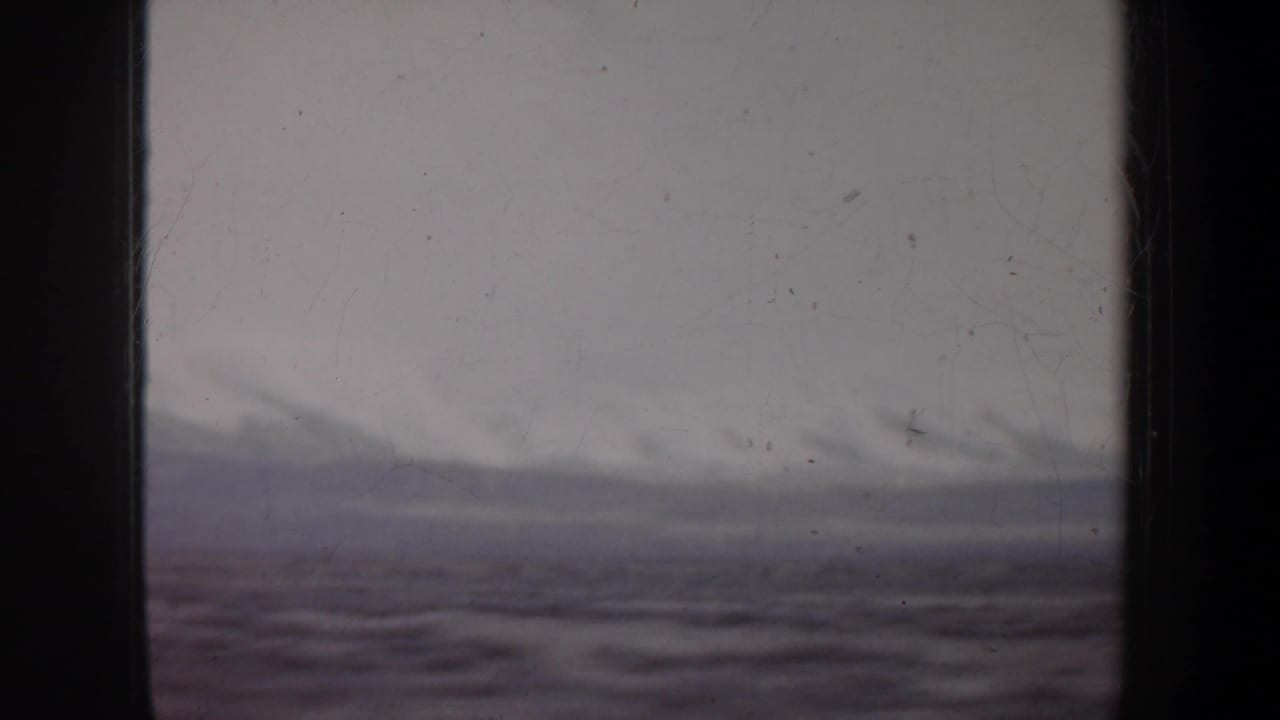 A moving 8mm view of Wyoming landscape, with low cloudy hills and blurred foreground terrain.