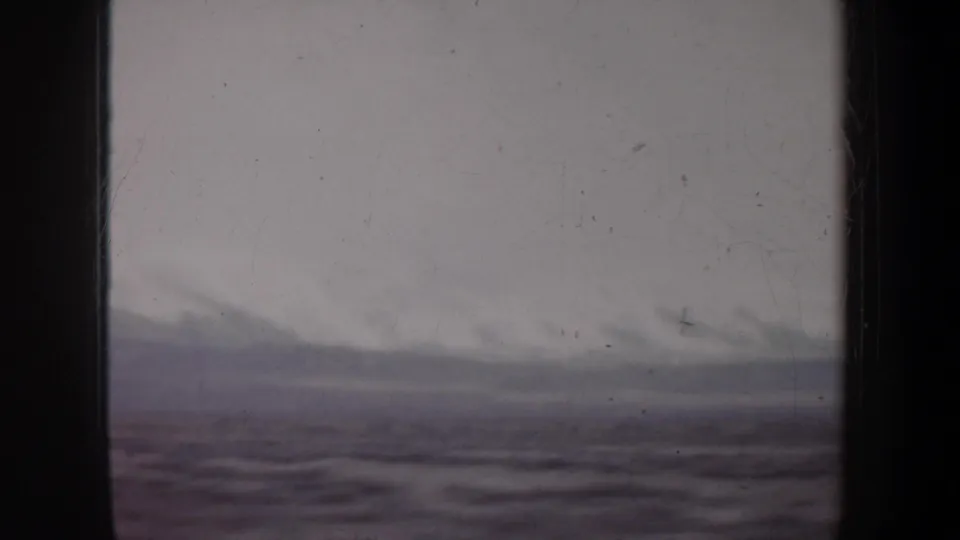 A moving 8mm view of Wyoming landscape, with low cloudy hills and blurred foreground terrain.