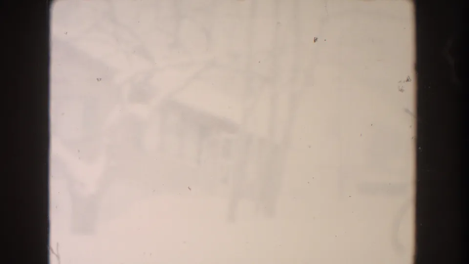 Soft 1961 Dearborn winter view with indistinct houses behind bare trees and a washed, grainy 8mm appearance.