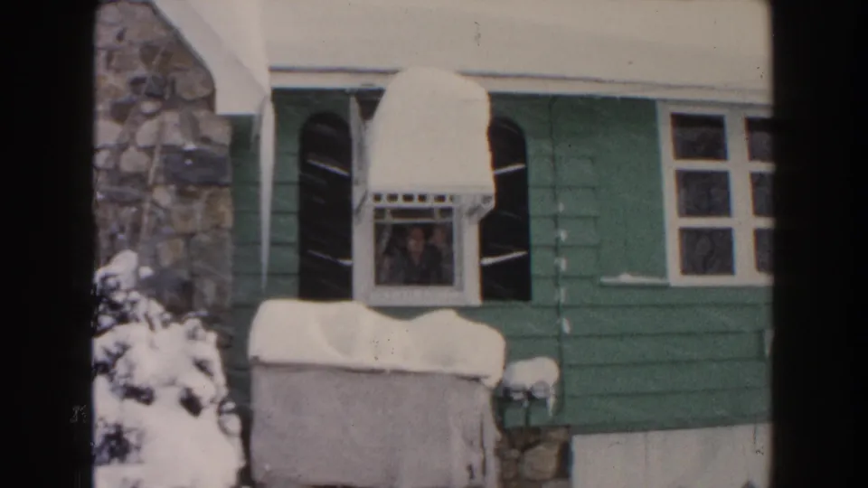 Dearborn, Michigan 1961 home-movie still showing a snow-covered house and a person at the window.