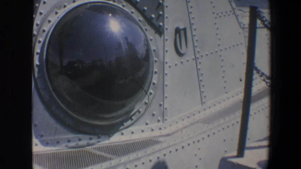 1973 Walt Disney World frame showing a dark domed submarine porthole with reflected visitors, chain rail, and riveted metal panels.