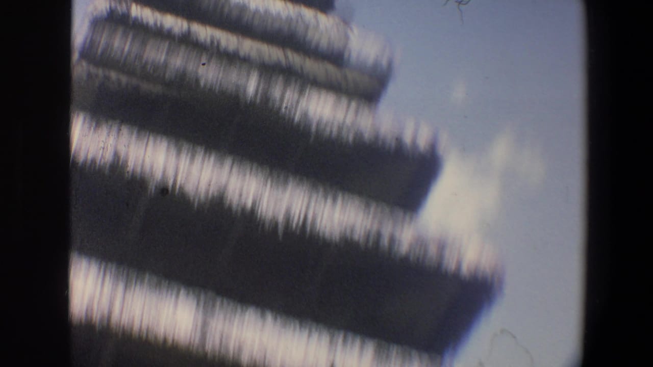Soft, motion-blurred 8mm frame from the Walt Disney World clip showing a dark layered roof or thatch edge against pale sky.