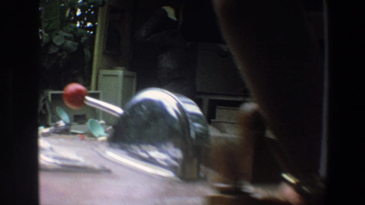 Gorilla enclosure viewed past a red control handle inside a ride vehicle.