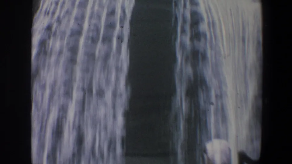 Home-movie view of falling water at Walt Disney World, with a dark structural shape and visible 8mm frame edges.