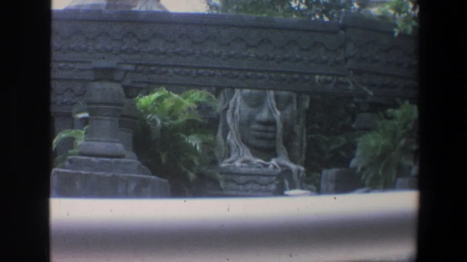 1973 Walt Disney World attraction scenery with carved stonework, a seated statue-like figure, plants, and a pale exposure band.