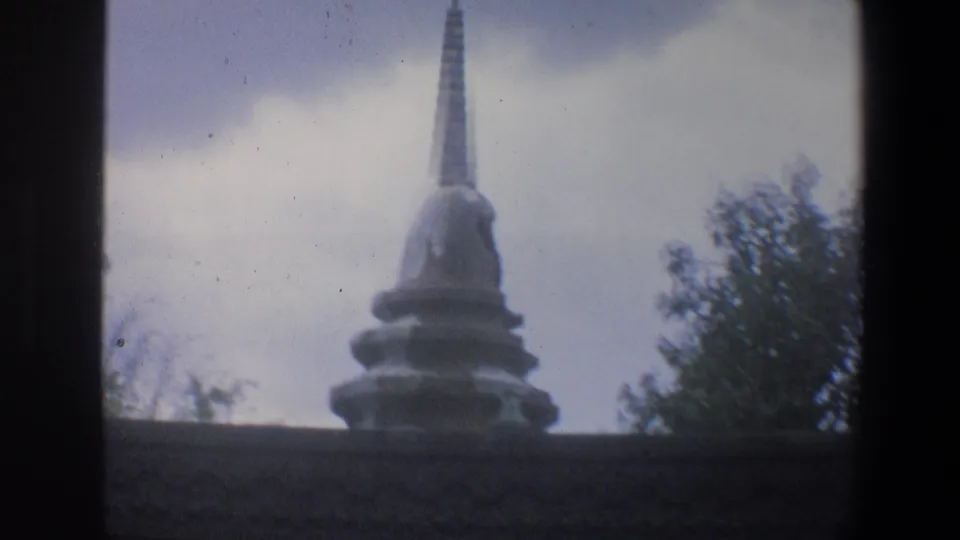 1973 Walt Disney World home-movie frame showing a spired stone roofline or set piece against trees and overcast sky.