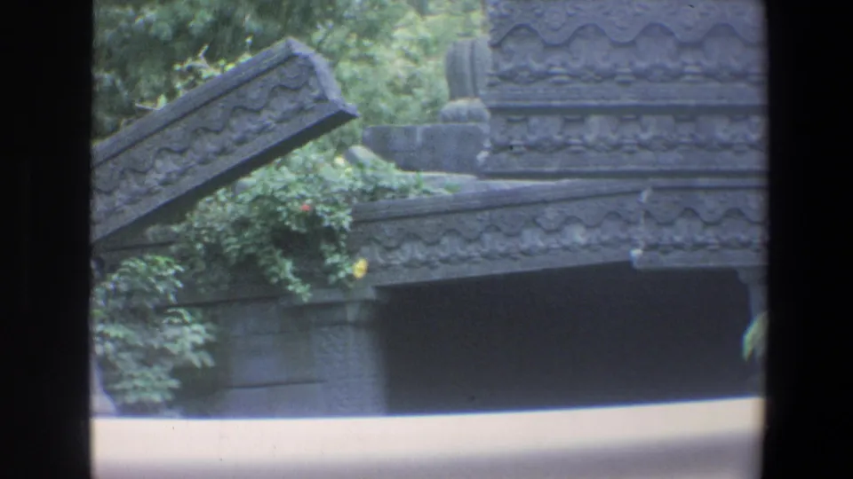1973 Walt Disney World frame with carved stone railings, layered set pieces, vines, greenery, and visible 8mm exposure banding.