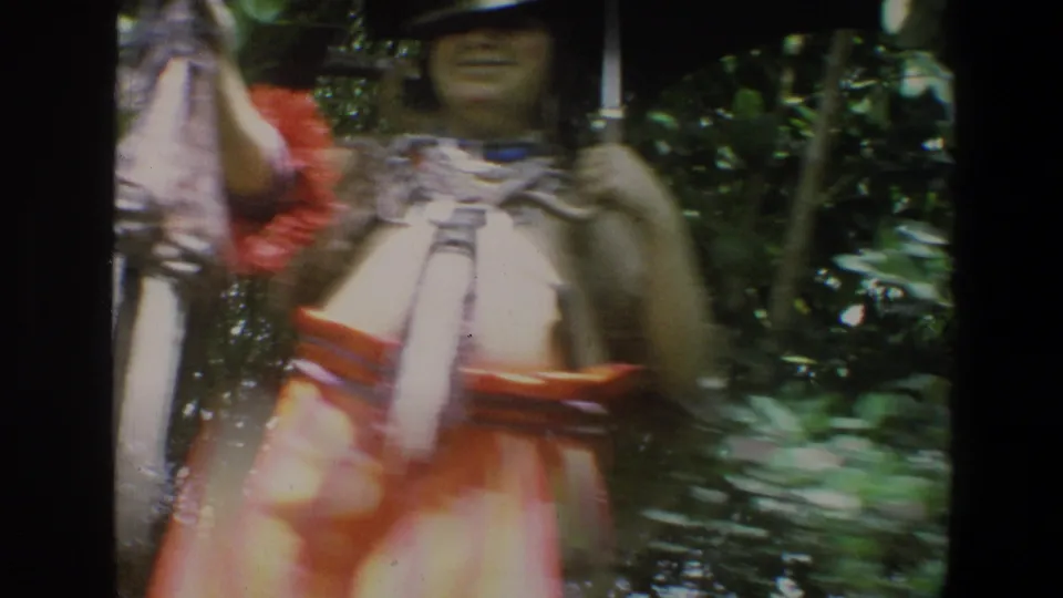 1973 Walt Disney World home-movie frame with a costumed performer holding a lantern amid greenery, face partly visible.
