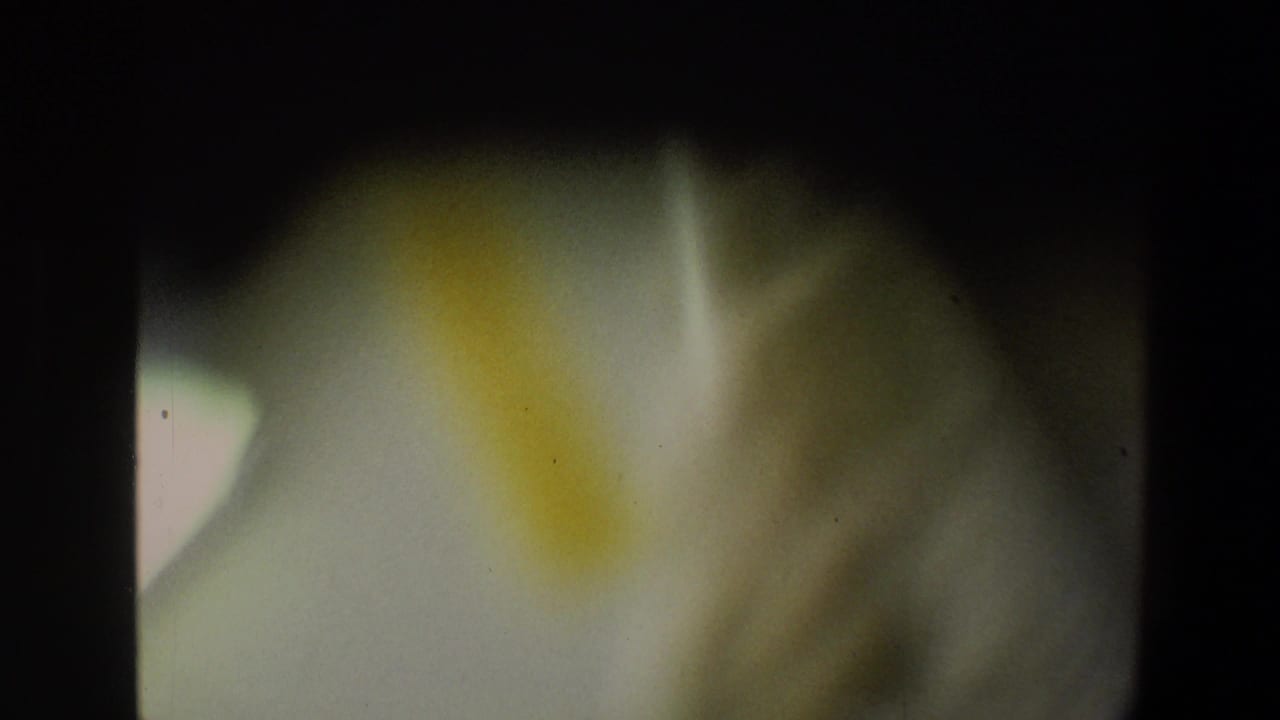Blurred 1973 Walt Disney World home-movie frame with green-yellow light, dark borders, and no identifiable people or signage.