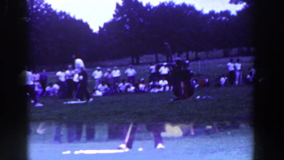 1961 Ridgefield, New Jersey 8mm frame showing a distant golf scene with spectators on the grass and a club or marker near the foreground.