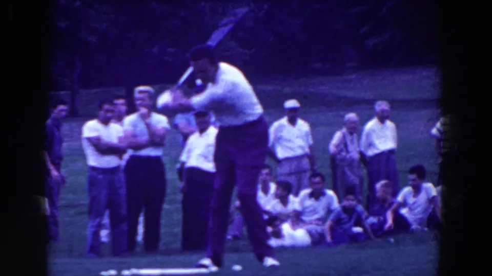 1961 Ridgefield, New Jersey frame with a golfer addressing the ball as standing and seated spectators watch nearby.