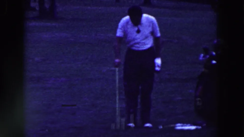 A male golfer in a white polo stands over a ball on grass, with a golf bag nearby in 1961 Ridgefield, New Jersey footage.