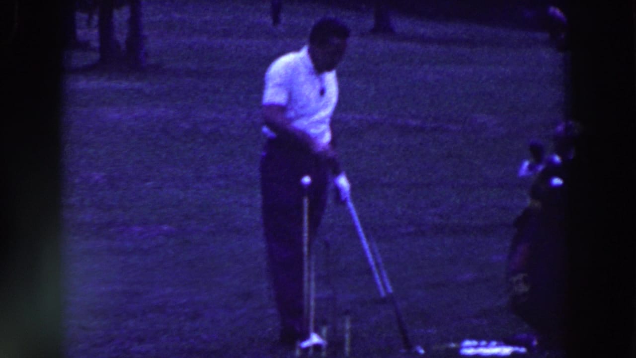 In Ridgefield, New Jersey in 1961, a man in a white shirt prepares a golf shot on a grassy course with trees behind him.