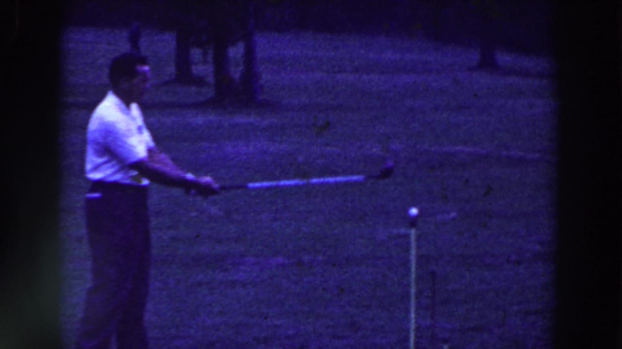 In 1961 Ridgefield, New Jersey home-movie footage, a man in a white shirt prepares to strike a golf ball on a grassy course.