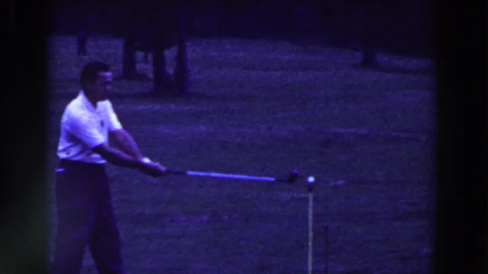 The golfer begins his swing in the 1961 Ridgefield, New Jersey 8mm footage, with the ball and tee marker visible ahead of him.