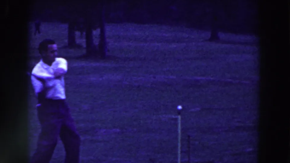 A man in a white shirt follows through after a golf swing in grainy 1961 Ridgefield, New Jersey home-movie footage.