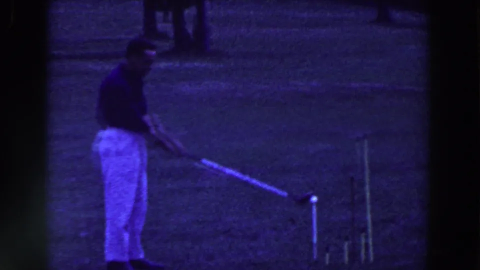 A golfer in dark shirt and light trousers stands near a tee marker on the grassy course in the 1961 Ridgefield, New Jersey reel.