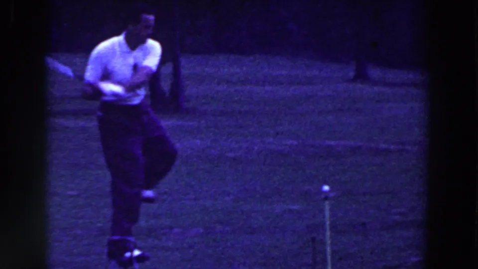 In Ridgefield, New Jersey in 1961, a man in a white shirt and dark trousers stands on grass with a golf club in vintage 8mm footage.