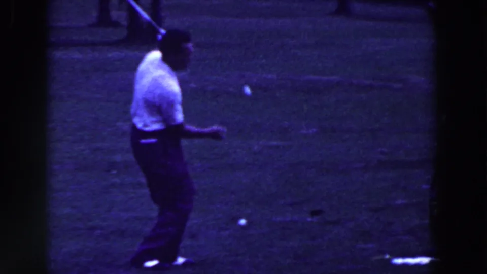 A golf ball appears suspended near the man as he holds the club after a trick movement in 1961 Ridgefield, New Jersey footage.