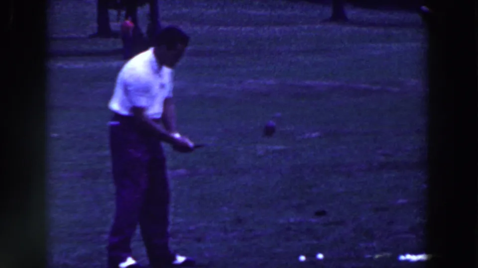 A man in dark trousers follows through on a golf swing in grainy 1961 Ridgefield home-movie footage.