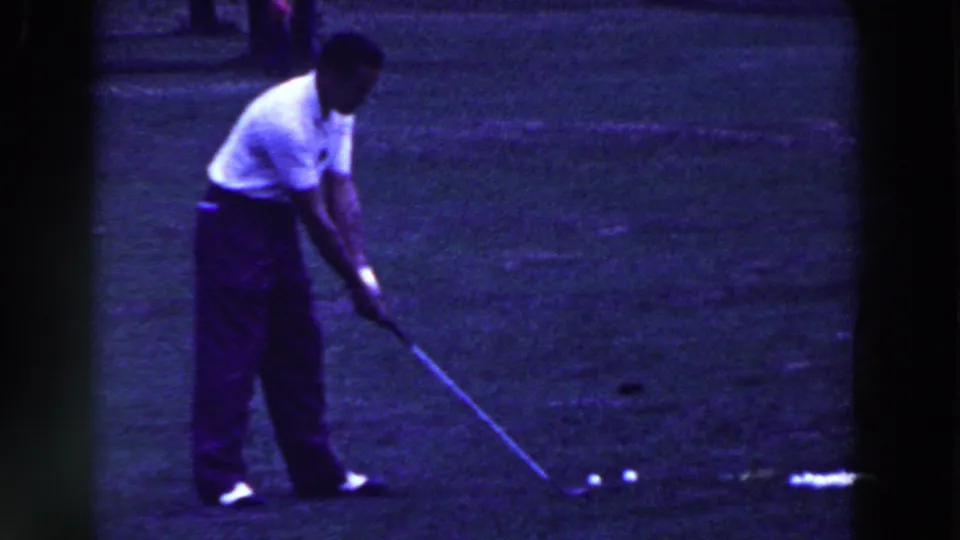 The golfer leans toward the ground with his club near several balls in the Ridgefield, New Jersey, 1961 8mm clip.