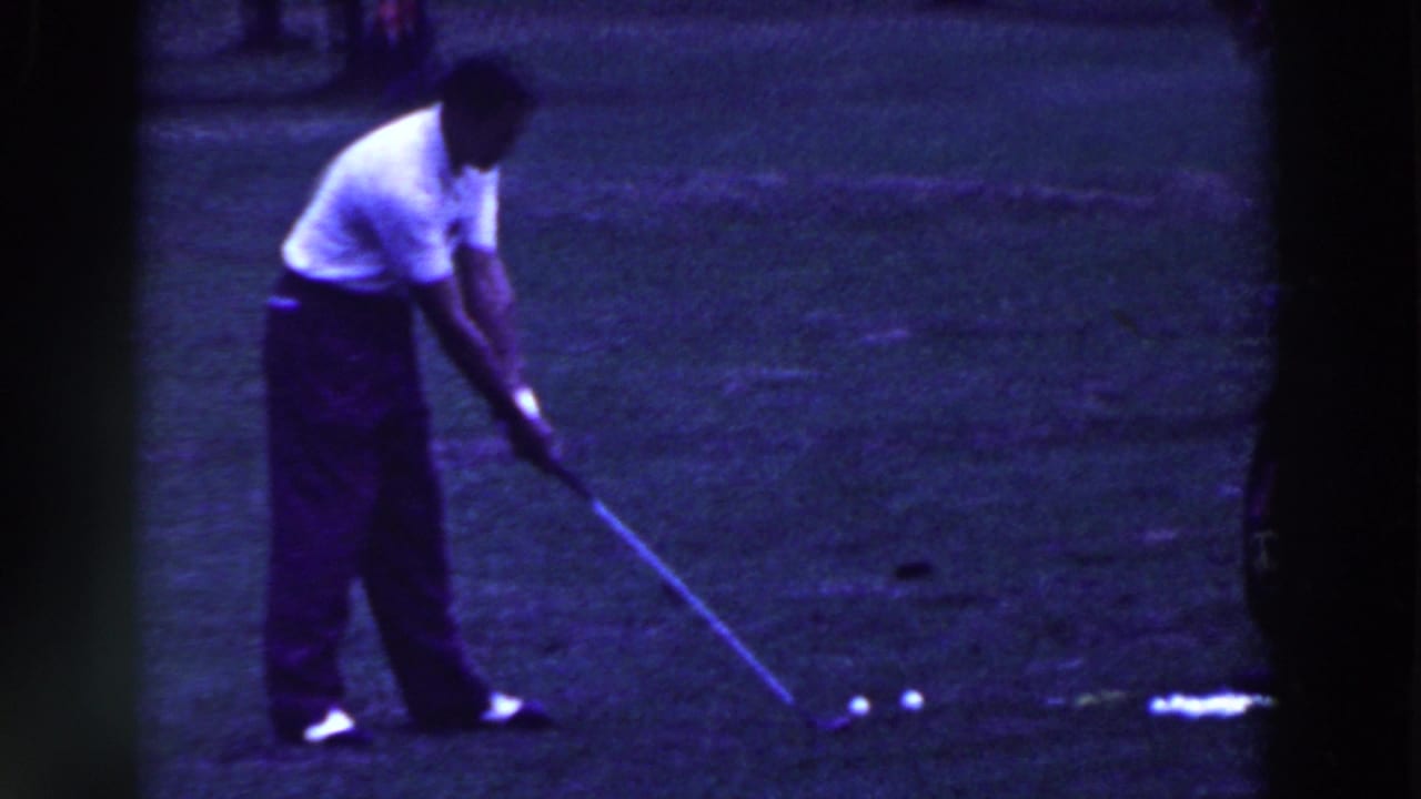 In 1961 Ridgefield, New Jersey footage, a man in a white shirt addresses a golf ball on a grassy course.