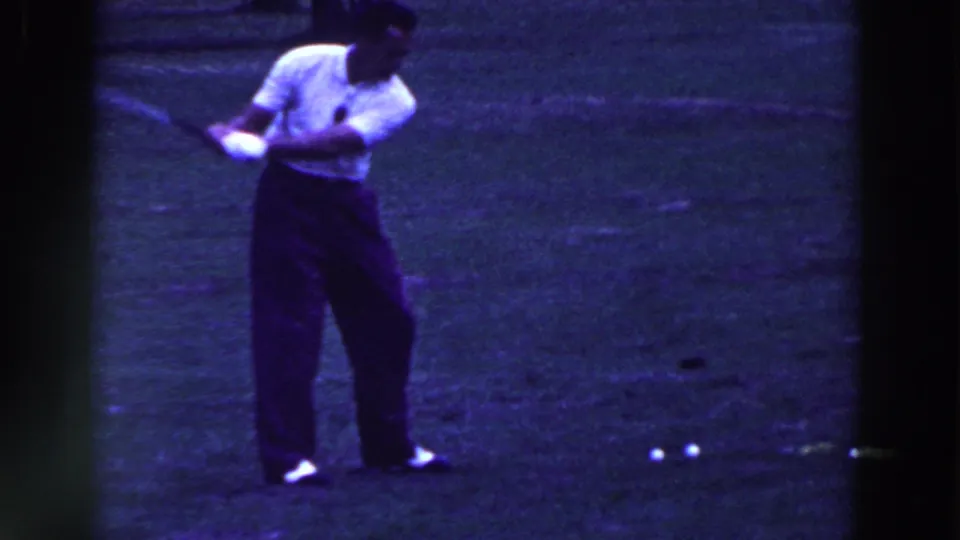 A man in a white polo and dark trousers follows through on a golf swing in the 1961 Ridgefield scene.
