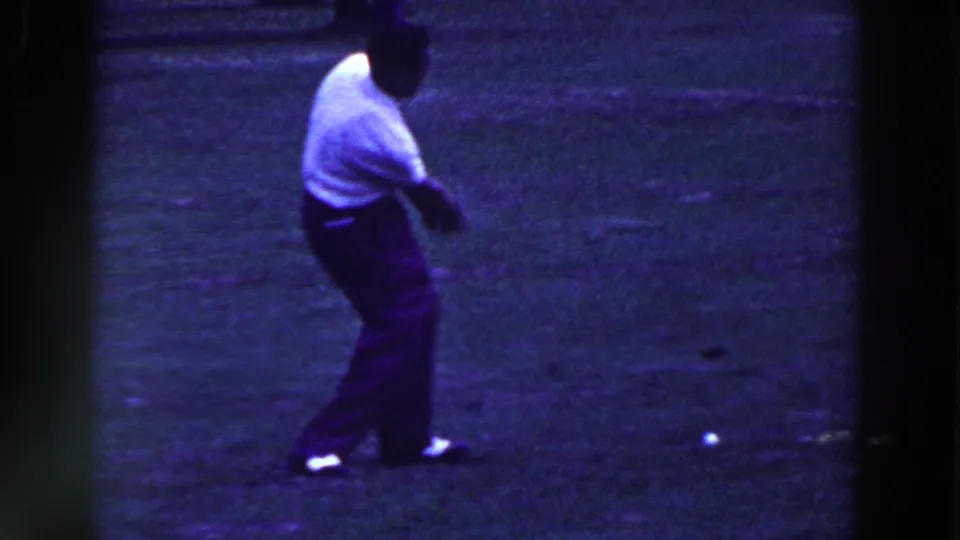 The golfer remains on the grassy Ridgefield course after a swing, with his club low and a ball nearby.