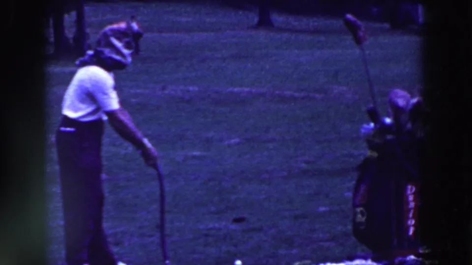 The man prepares to putt near a standing golf bag, with blue-purple 8mm color shift across the frame.
