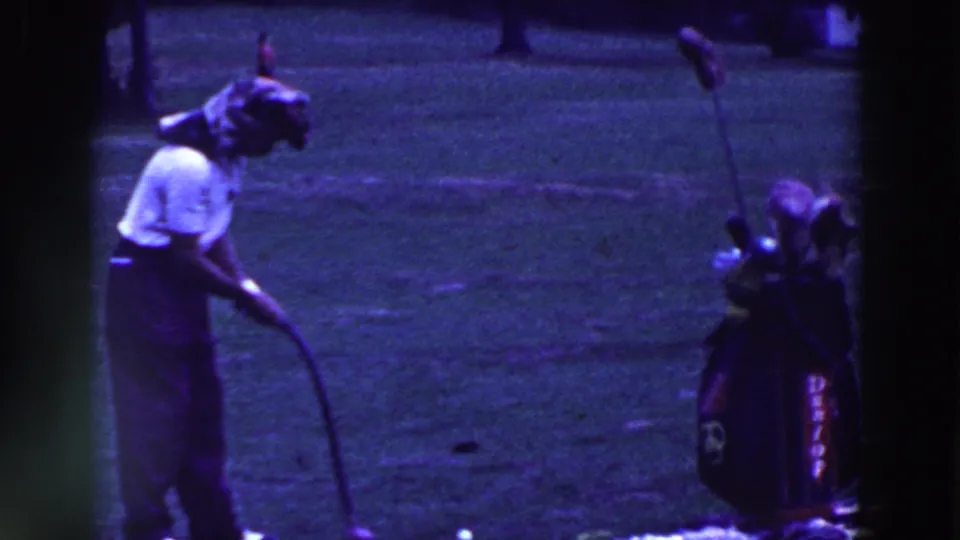 In 1961 Ridgefield, New Jersey footage, a man in a white shirt leans toward a golf ball near a standing golf bag on a grassy course.