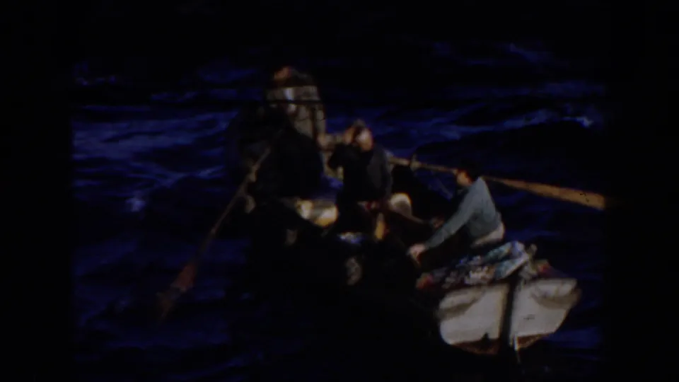 1959 Gibraltar home-movie frame showing several people in a small boat on dark blue water, with an oar extended from the side.