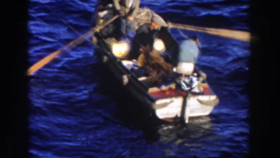 Near the end of the clip, the Gibraltar rowboat fills the frame with three men, visible gear, bright reflections, and oars over rough water.