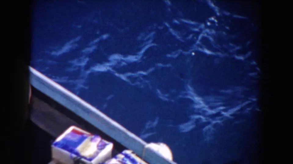 1959 Gibraltar home-movie view from a nearby boat, showing the rail, packed supplies, and choppy blue water.