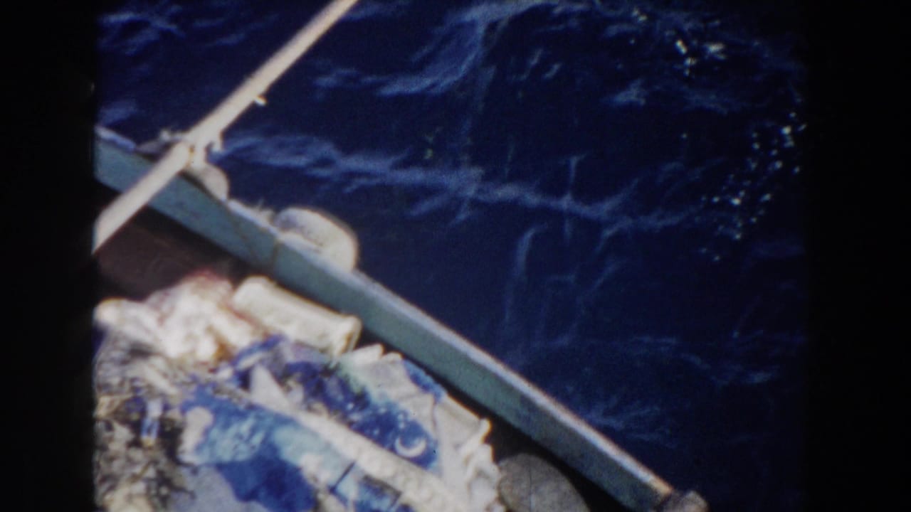 Boat rail and pale oar over dark blue water, with fabric bundles at the lower left.