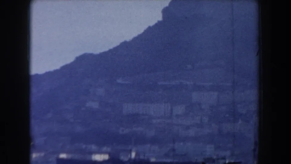 Rocky Gibraltar landscape and coastal buildings appear in a blue-tinted 8mm frame from the boat viewpoint.