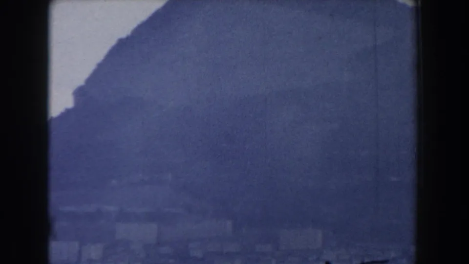 The final frame shows the Gibraltar hillside darkening across the view, with faint buildings below in soft 8mm texture.