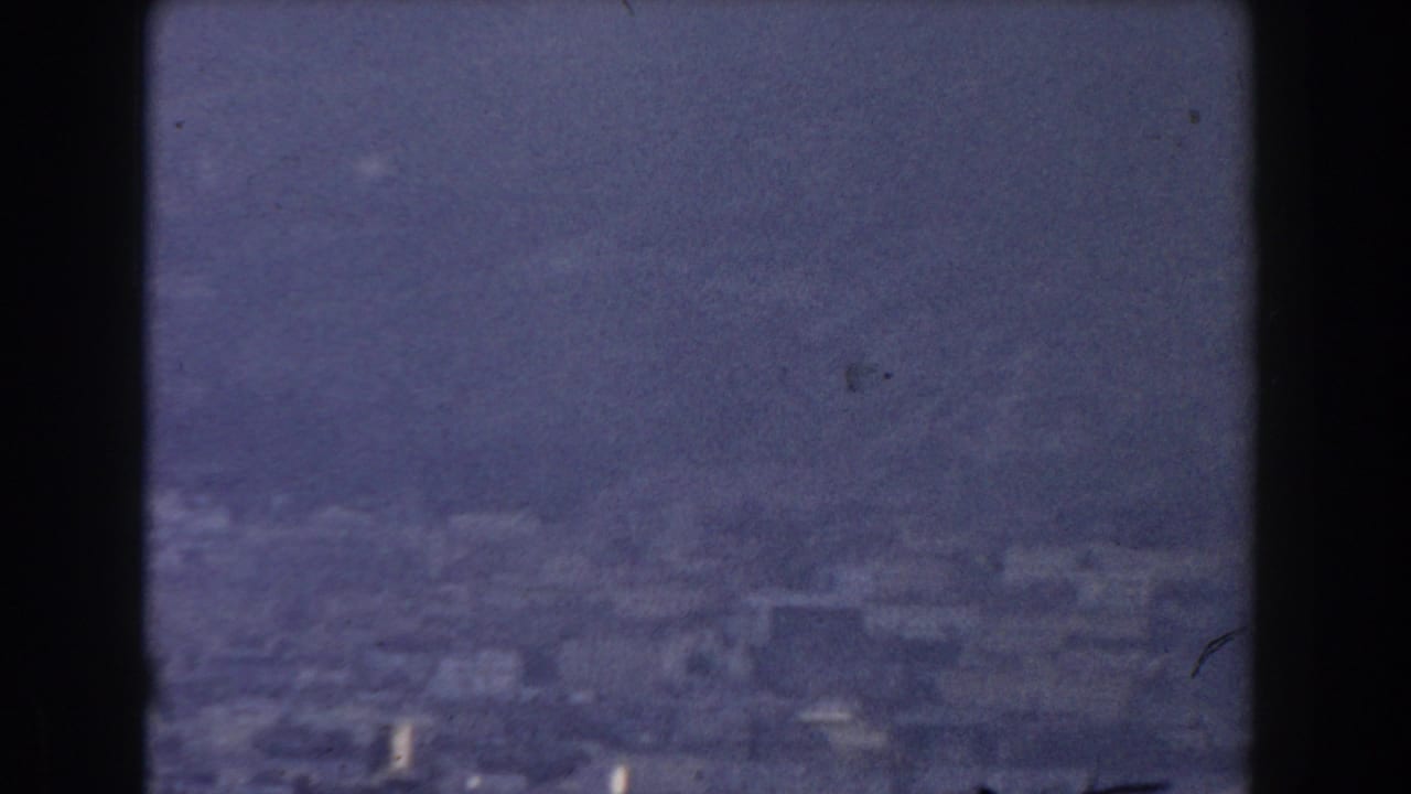Soft aerial view of clustered buildings under a hazy blue-grey sky.